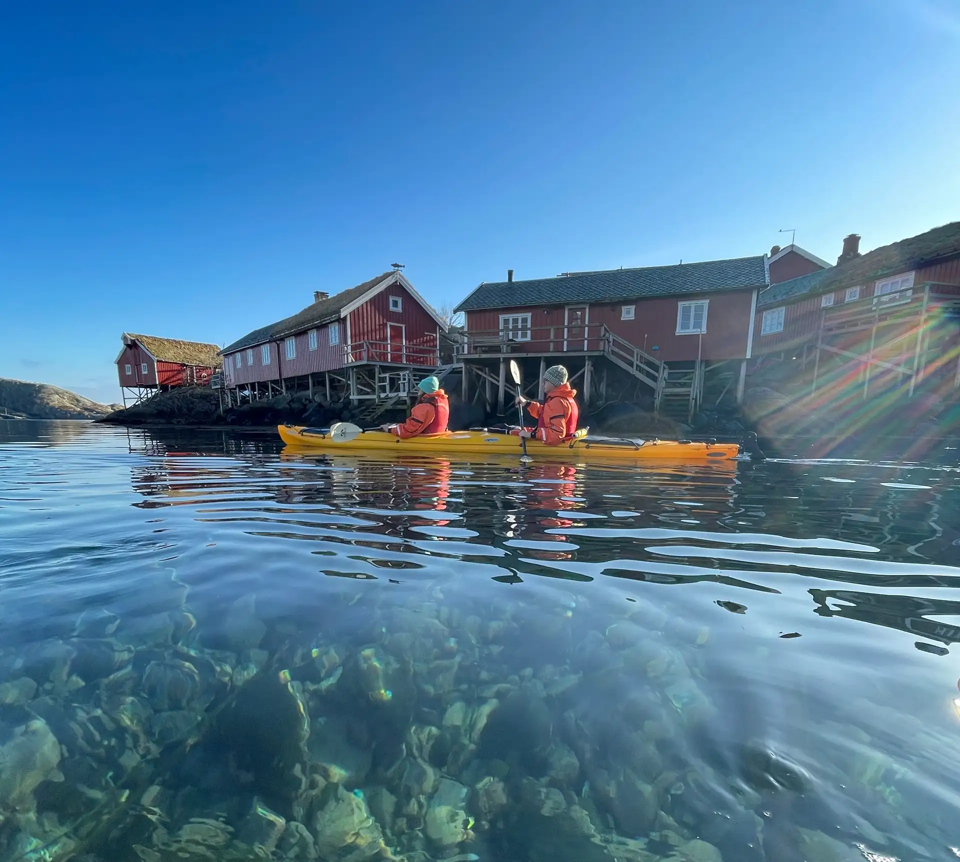 people-yellow-kayak-clear-water-blue-sky-red-houses