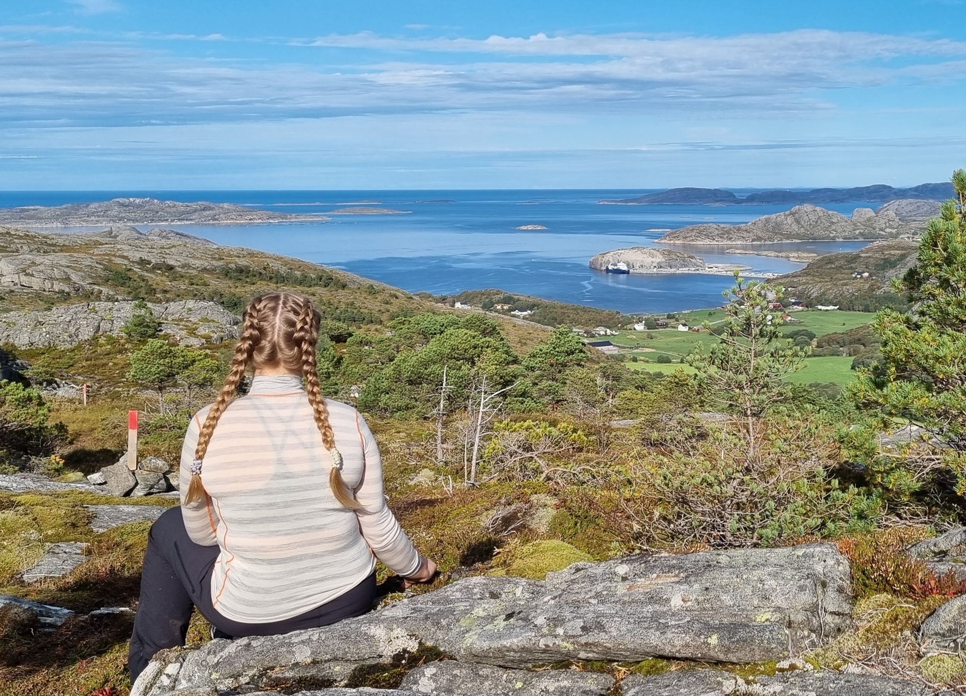 woman-sitting-atop-storskardheia-mountain-looking-onto-water-bessaker