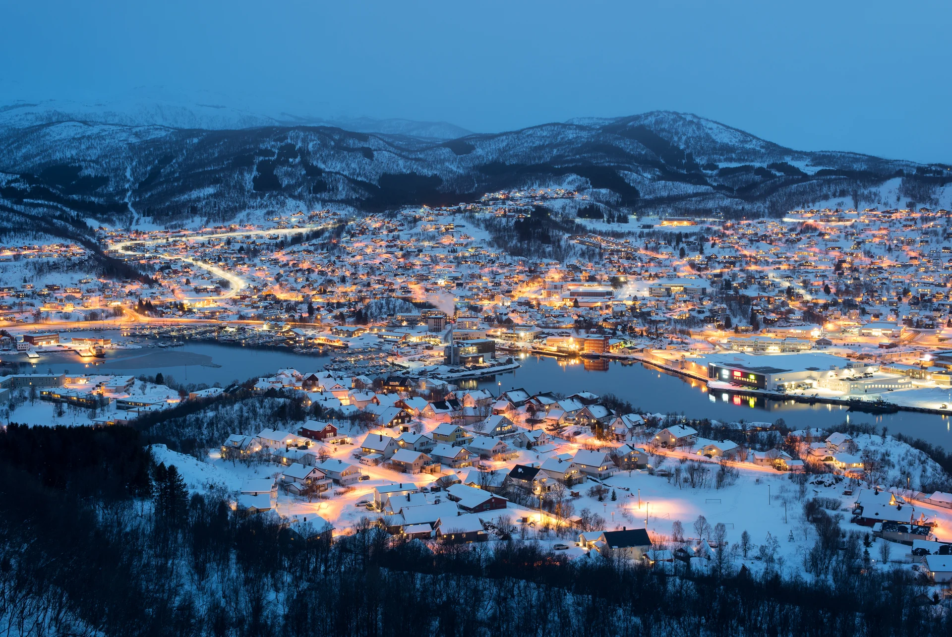 Vue aérienne nocturne de Harstad, en Norvège, avec la neige recouvrant les bâtiments.