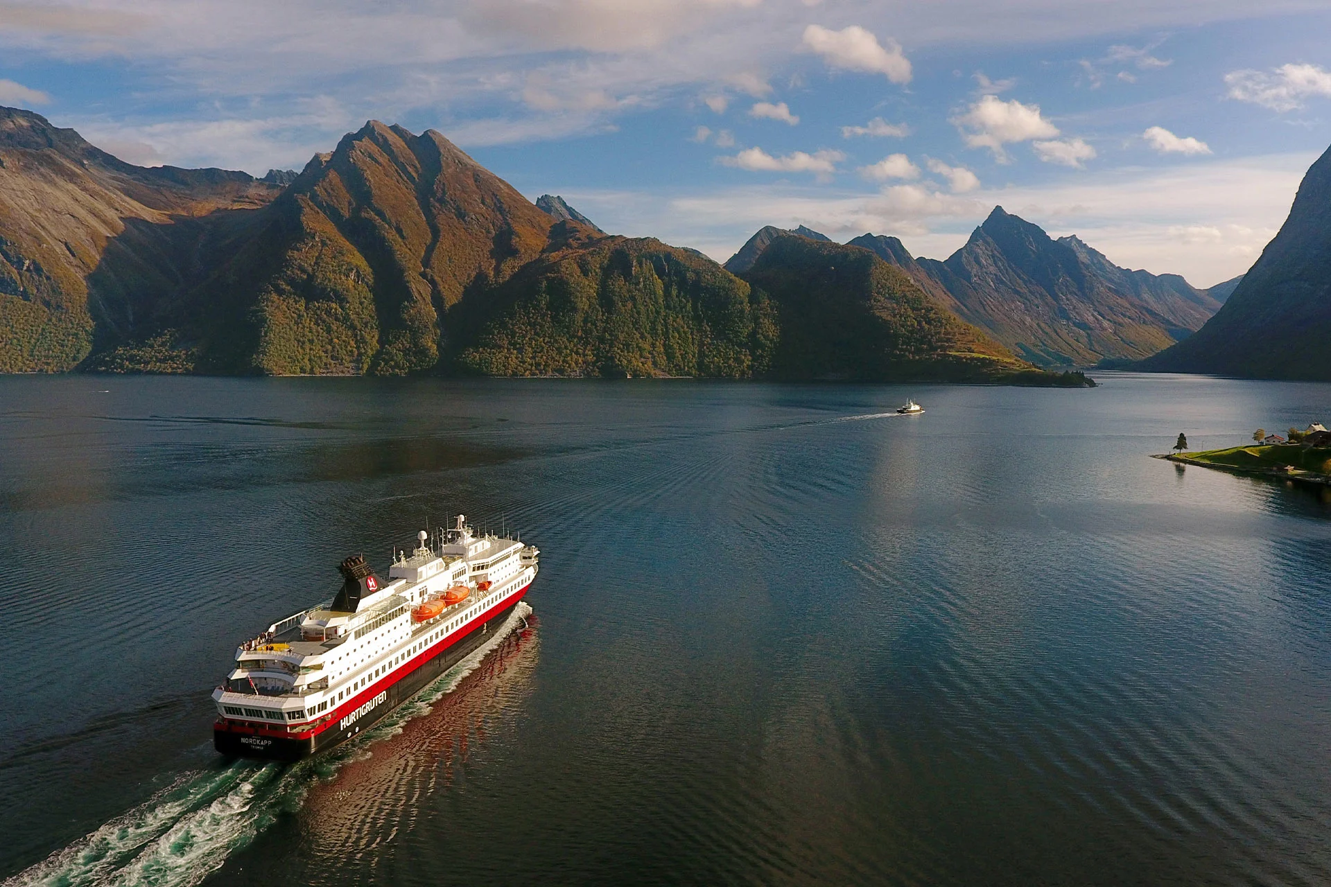 A Hurtigruten ship sailing in Hjørundfjord in autumn