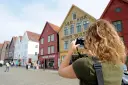 A tourist takes a photo of the wooden buildings in Bryggen, Bergen