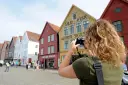 Un touriste prend une photo des bâtiments en bois de Bryggen, à Bergen.