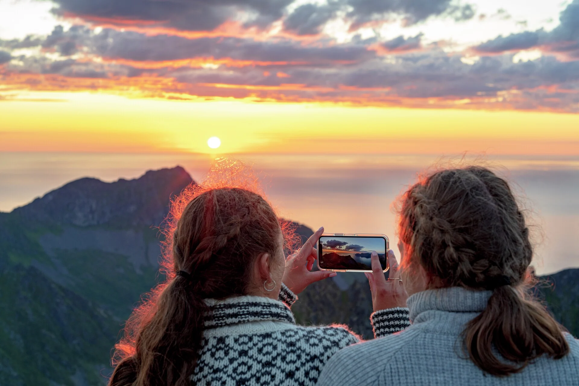 Two people capturing the Midnight Sun on mobile phone in Lofoten Norway by Getty Images
