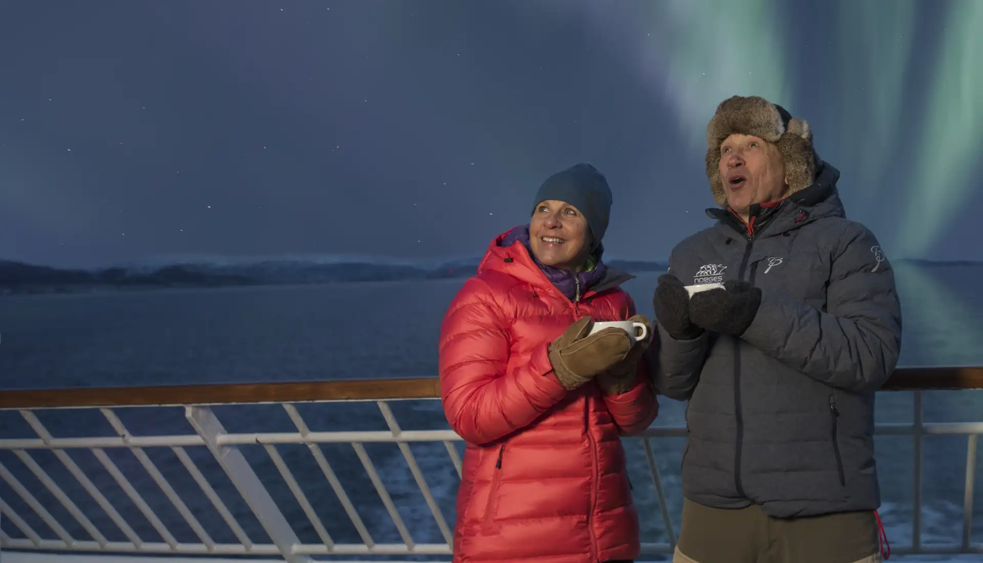 Passengers aboard a Hurtigruten Ship gaze at the Northern Lights at night