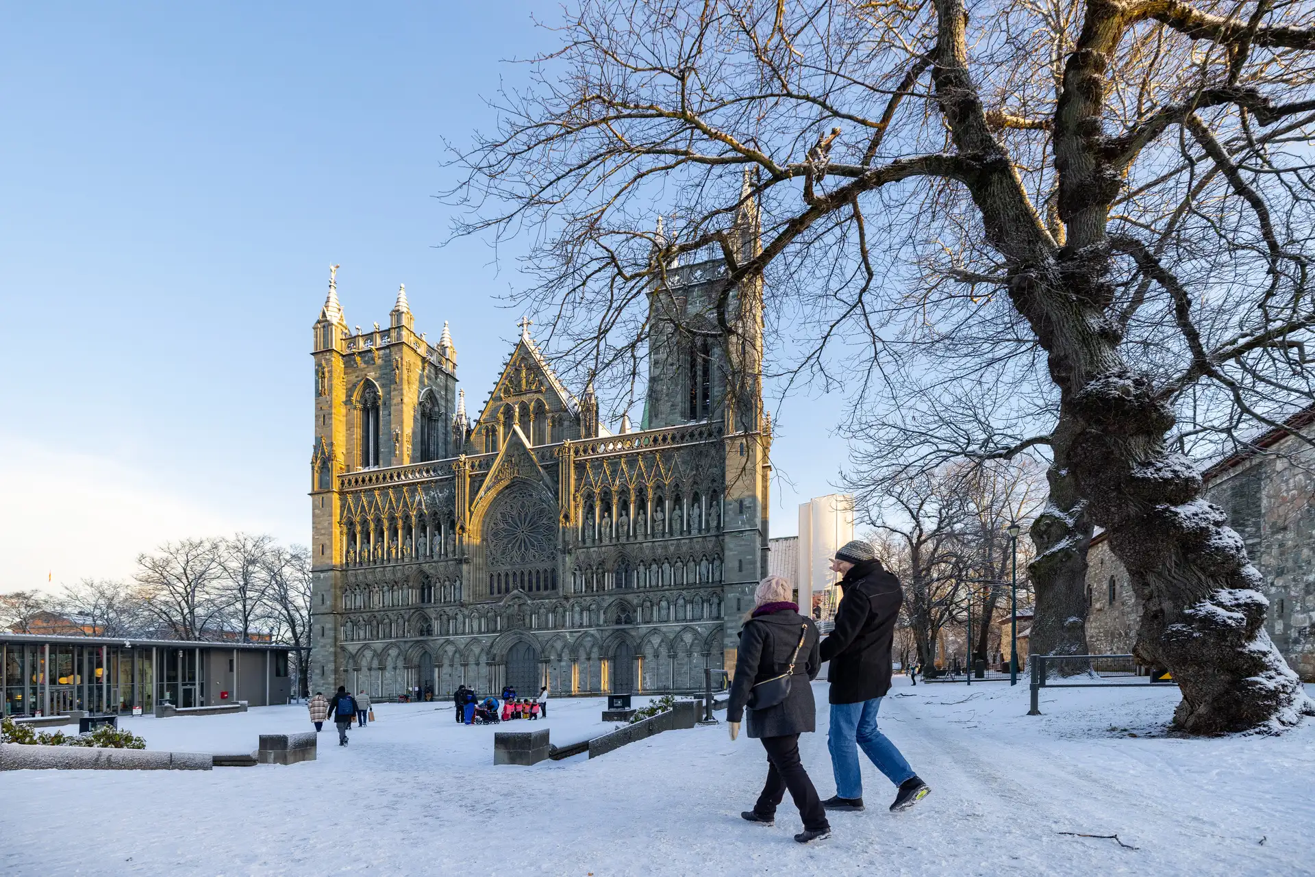A couple stroll through the snow in Trondheim to Nidaros Cathedral