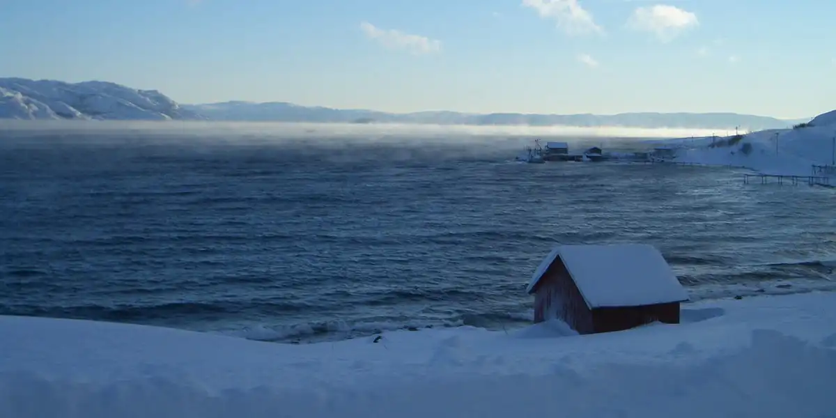 A snow-covered red cabin on the shores of the Altafjord in winter, Finnmark, Northern Norway