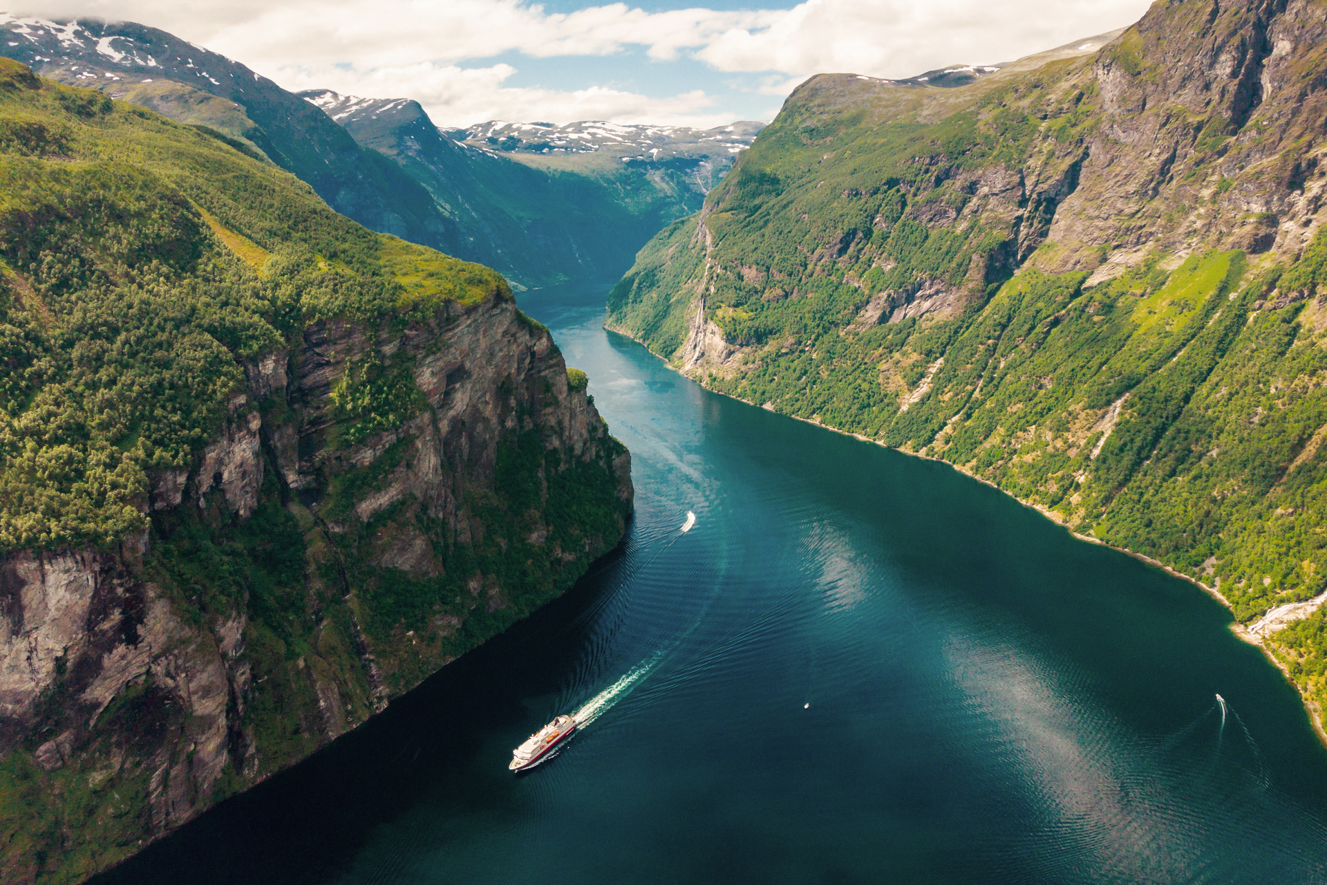 A Hurtigruten ship sailing through Geirangerfjord, often referred to as the “jewel in the crown” of the Norwegian fjords