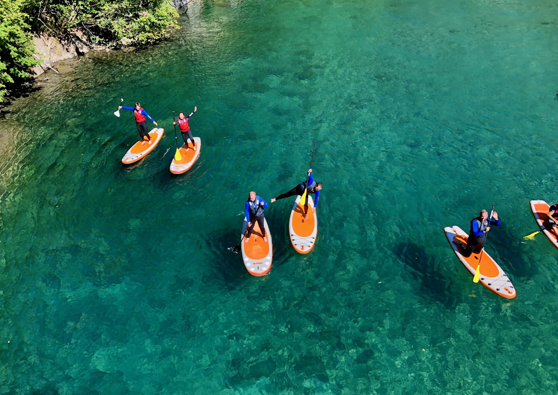 people-standing-orange-paddleboards-turquoise-water