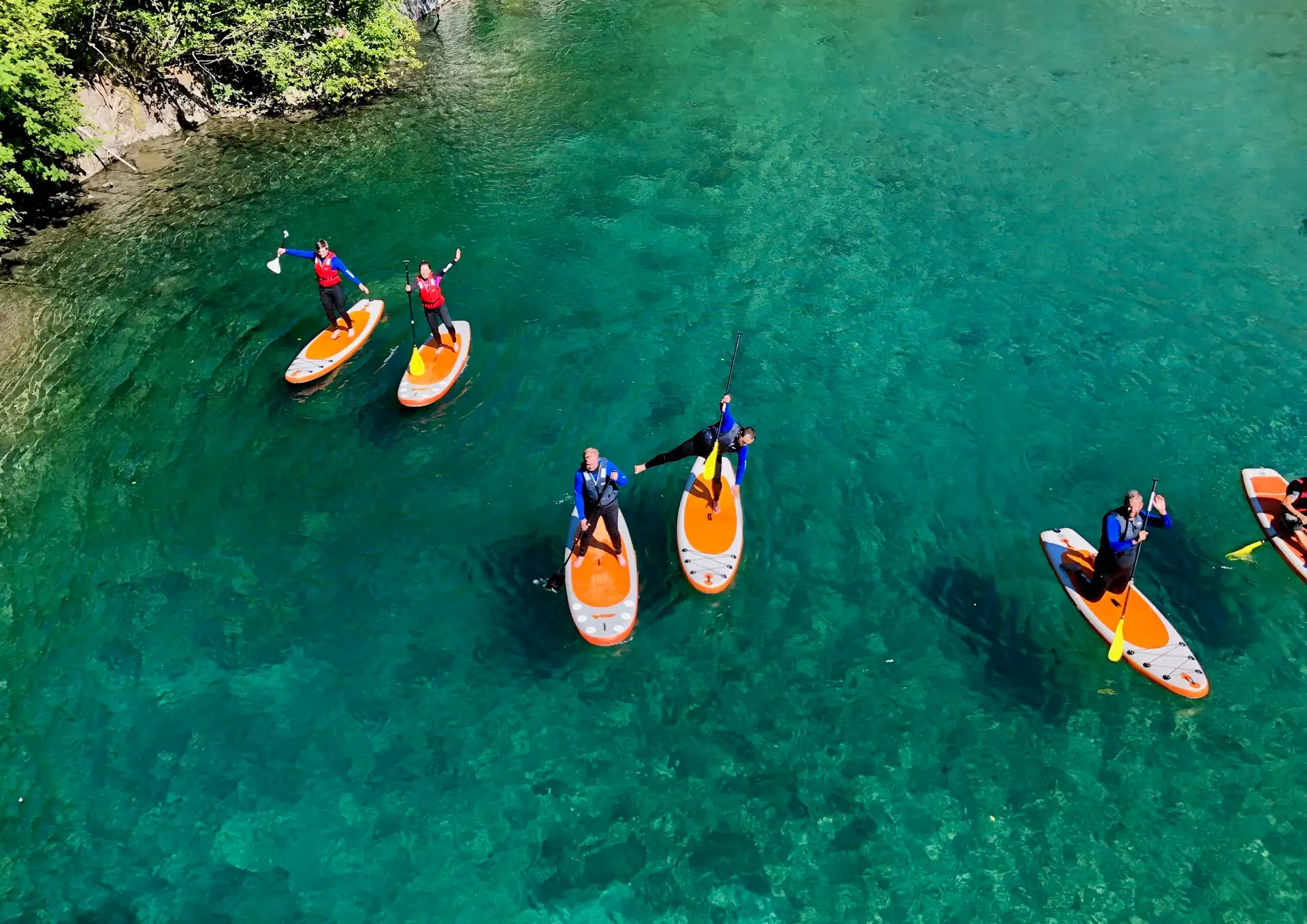 people-standing-orange-paddleboards-turquoise-water