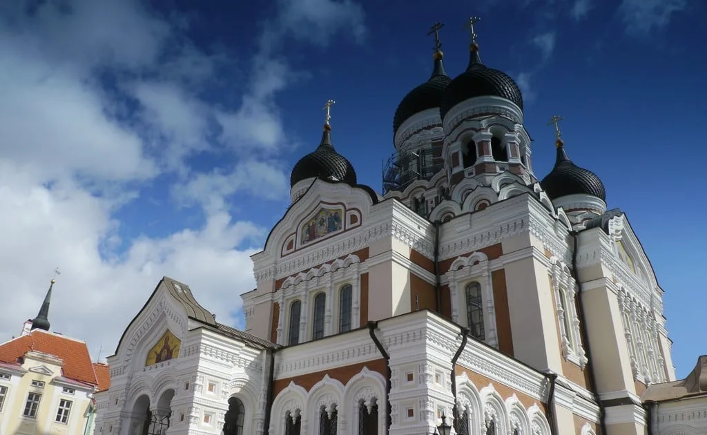 A church with a large white building with Alexander Nevsky Cathedral, Tallinn in the background