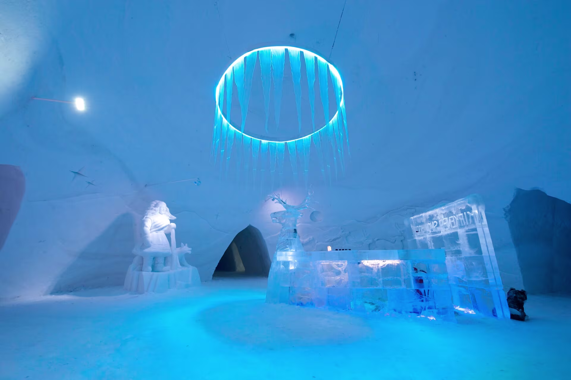 Inside the Kirkenes Snowhotel. A frozen blue chandelier, an ice front desk and snow walls