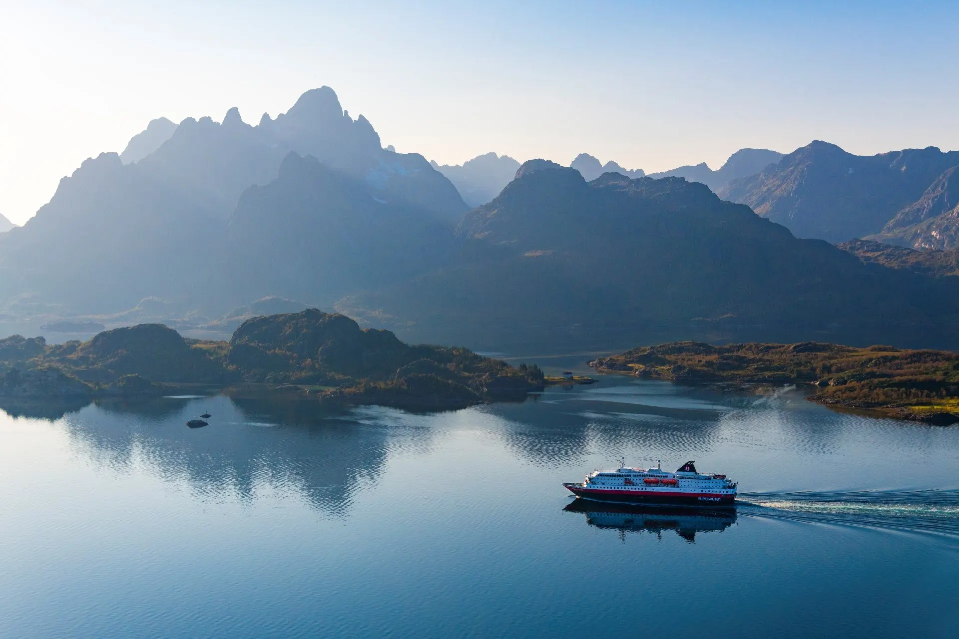 Hurtigruten Schiff im Raftsund, Norwegen. Das Wasser ist ruhig und der Himmel ist blau