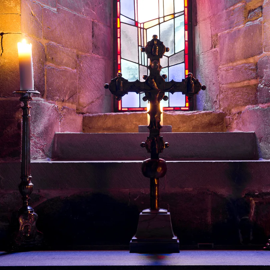 Les salles cachées de la cathédrale de Nidaros. La photo montre une croix et deux bougies allumées à l'intérieur de la cathédrale de Nidaros.
