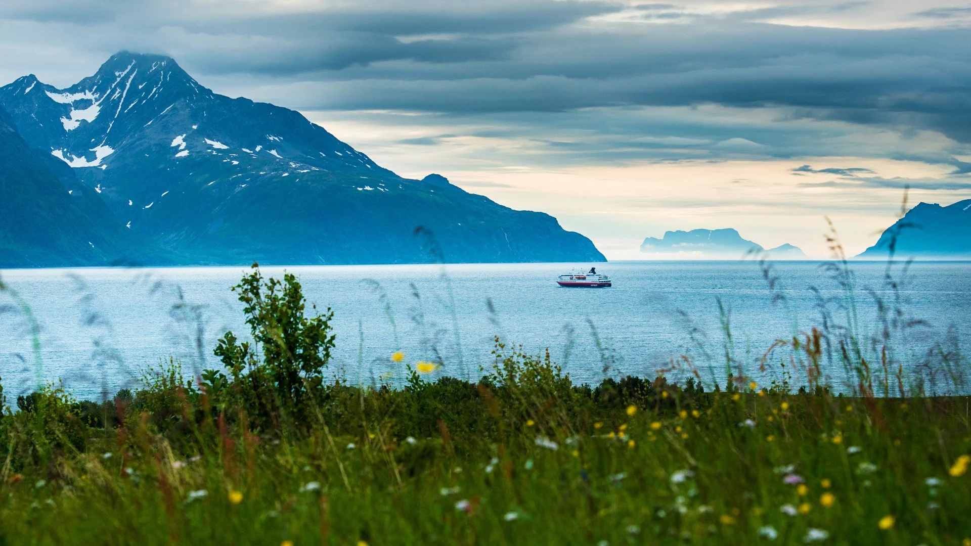 MS Nordnorge is sailing through Lyngenfjord, a mountain range in the Nothern Norway.