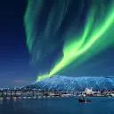 Beautiful Northern Lights dancing on the sky above the city of Tromsø and the Arctic Cathedral, Norway.