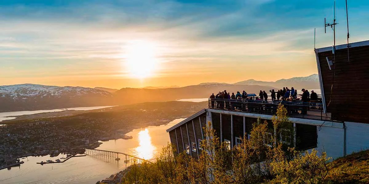 People standing on top of the Fjellheisen Cable car enjoying the sight of the midnight sun in Tromsø 