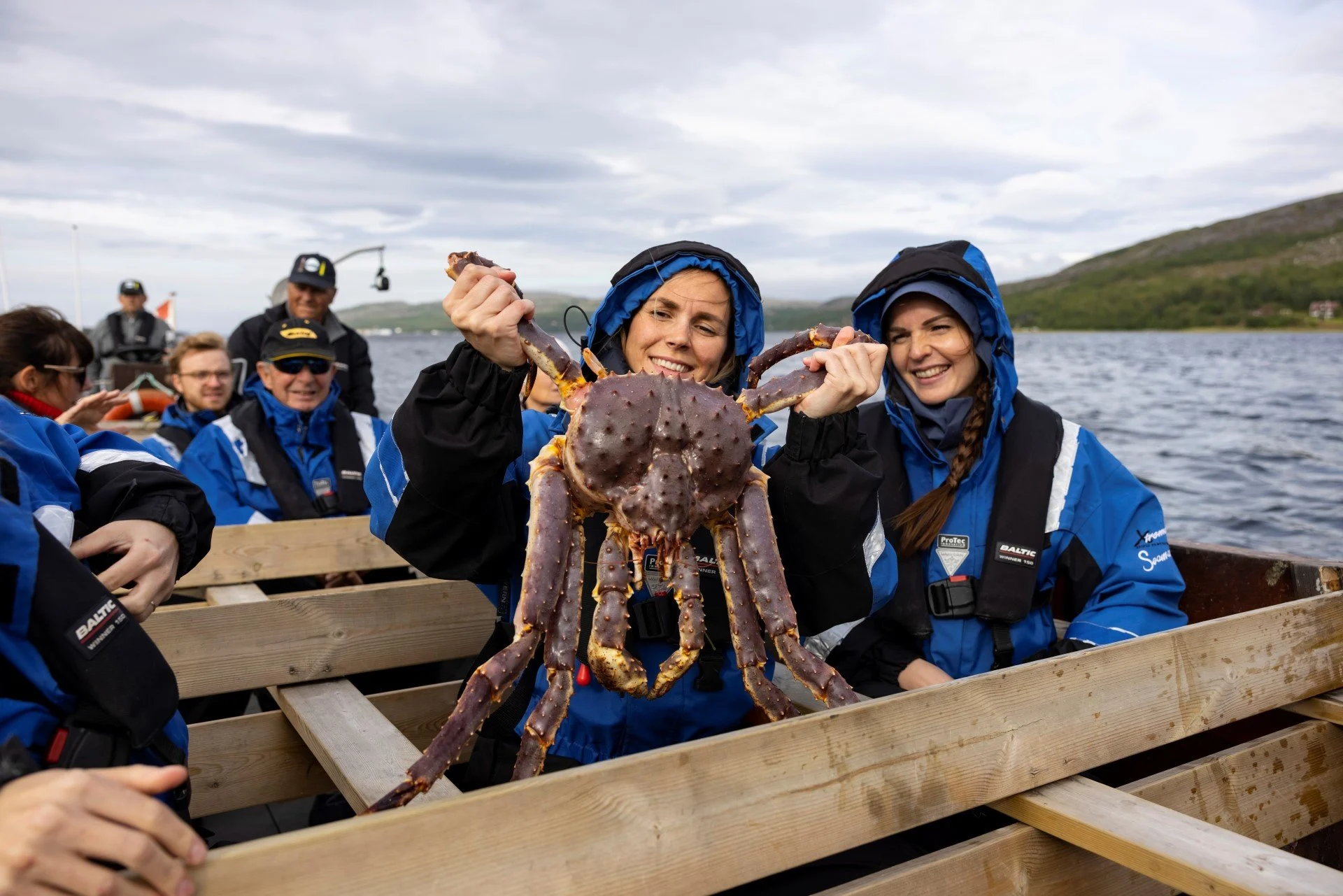 A girl holding a large king crab onboard during a king crab safari in northern norway