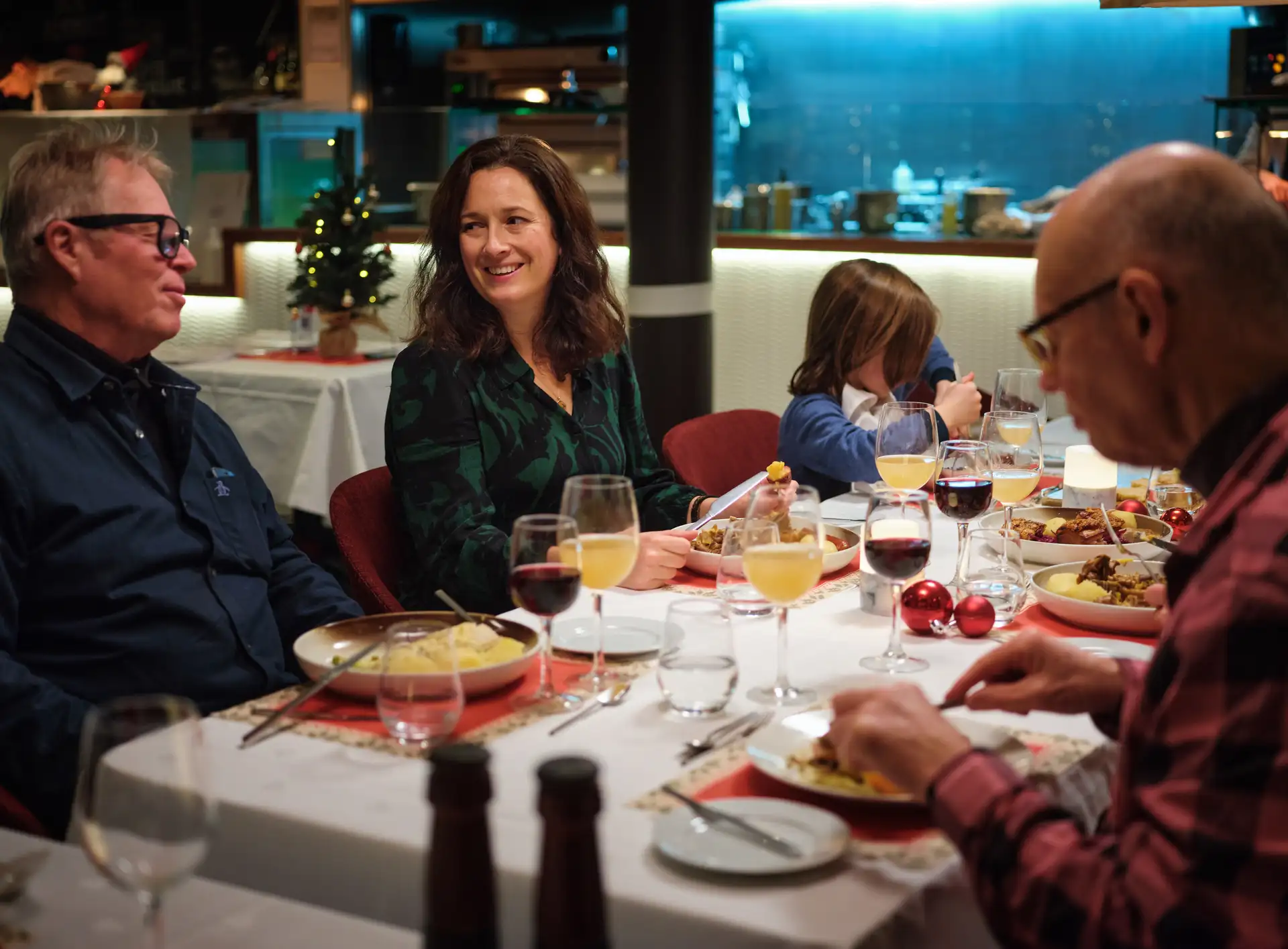 Eine Gruppe von Gästen geniesst ein festliches norwegisches Weihnachtsessen im Restaurant eines Hurtigruten Schiffes
