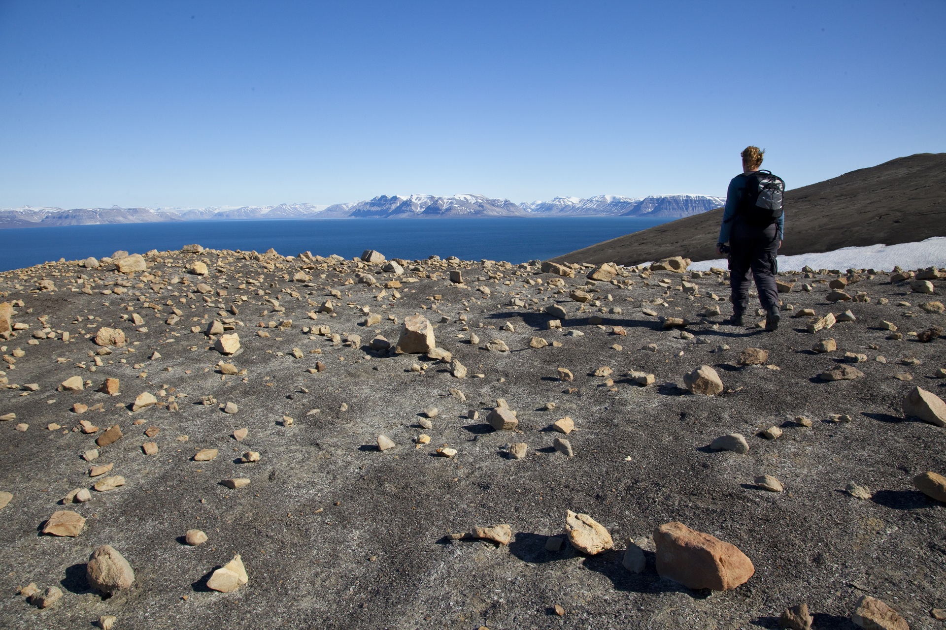 jakt-person-standing-on-glacier-svalbard-looking-onto-blue-water-hgs-08785-linda-drake