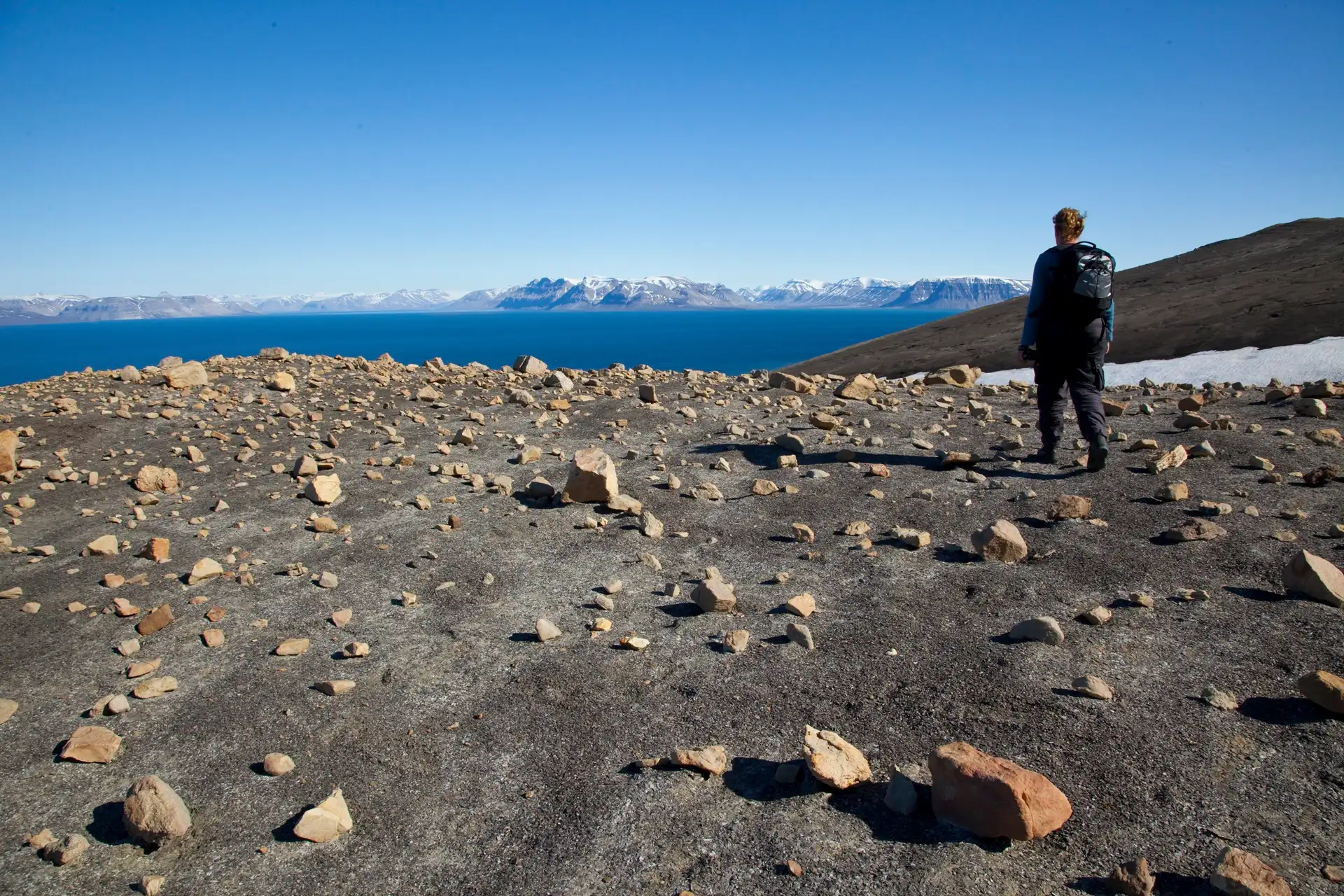 jakt-person-standing-on-glacier-svalbard-looking-onto-blue-water-hgs-08785-linda-drake