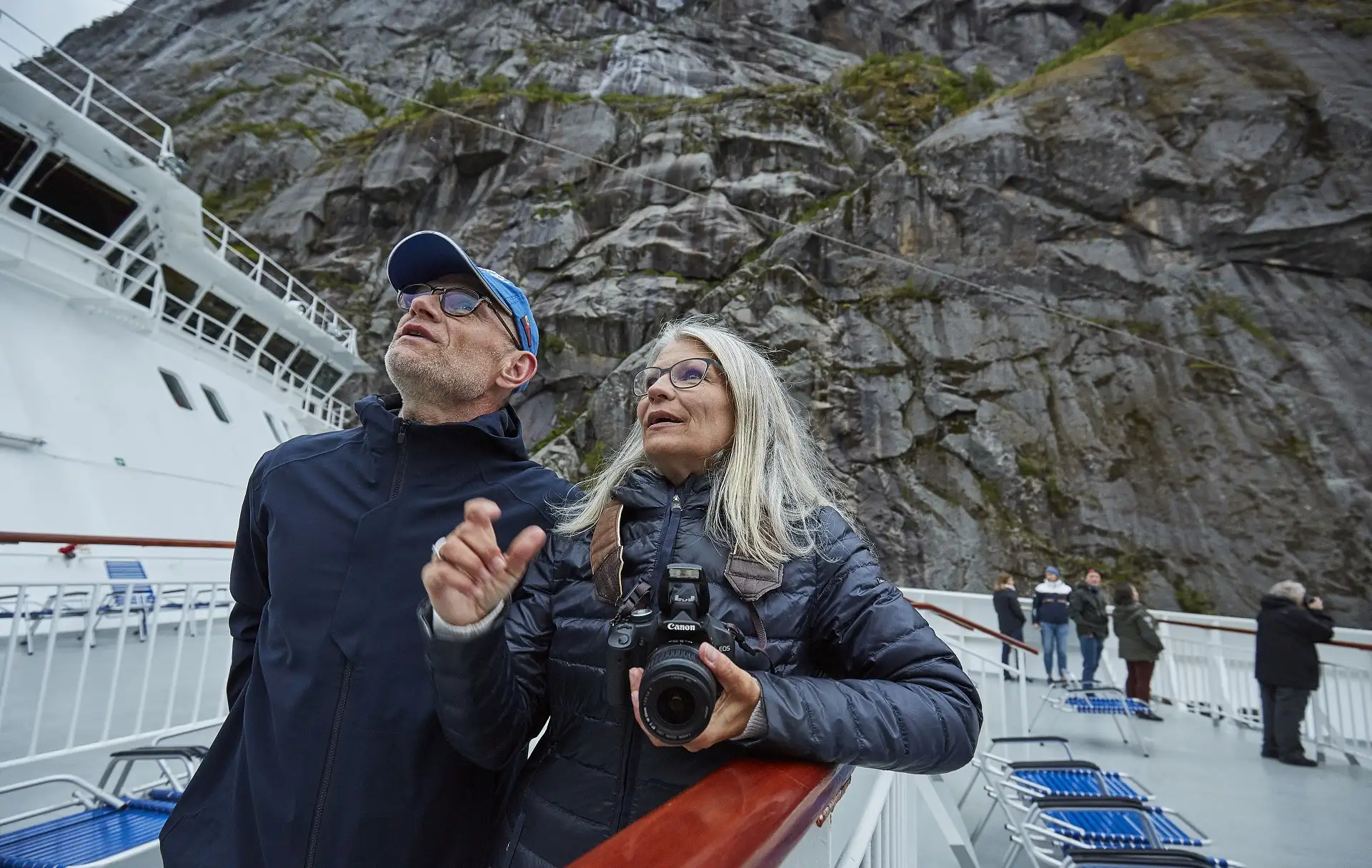 A couple on the deck of a Hurtigruten ship, enjoying the view of the Norwegian coast