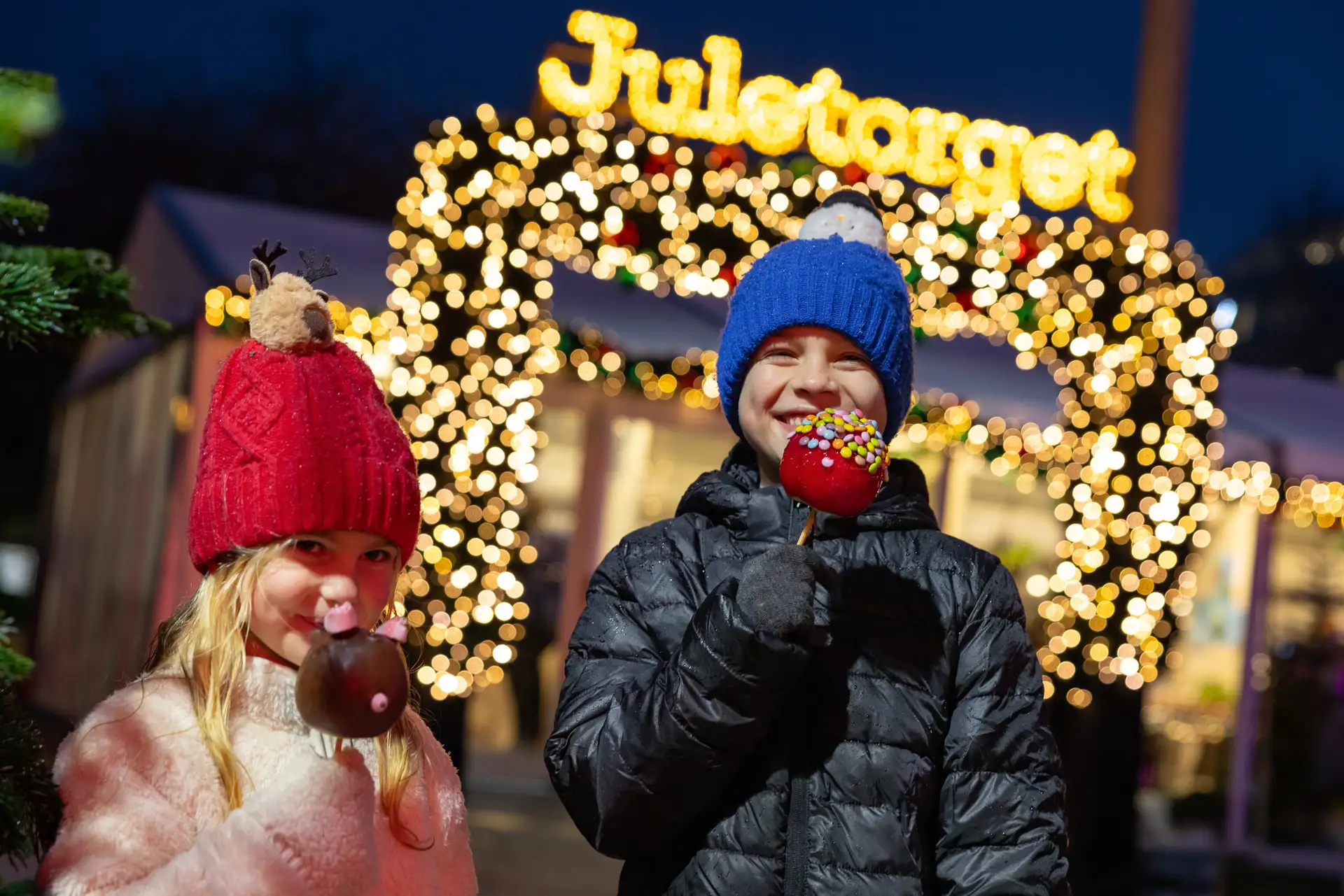 Children eating toffee apples at Juletorget Christmas market in Bergen, Norway