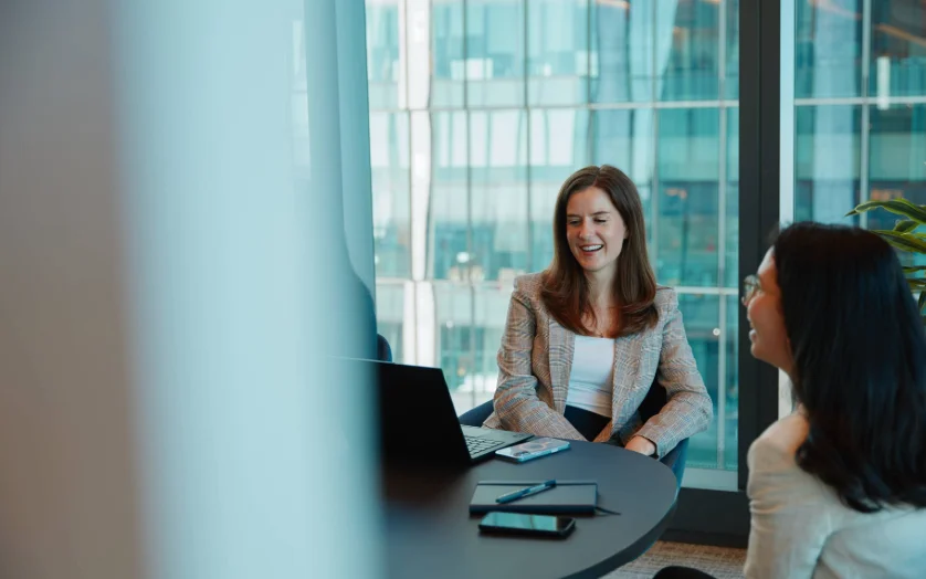 Two women sitting at a table with a laptop