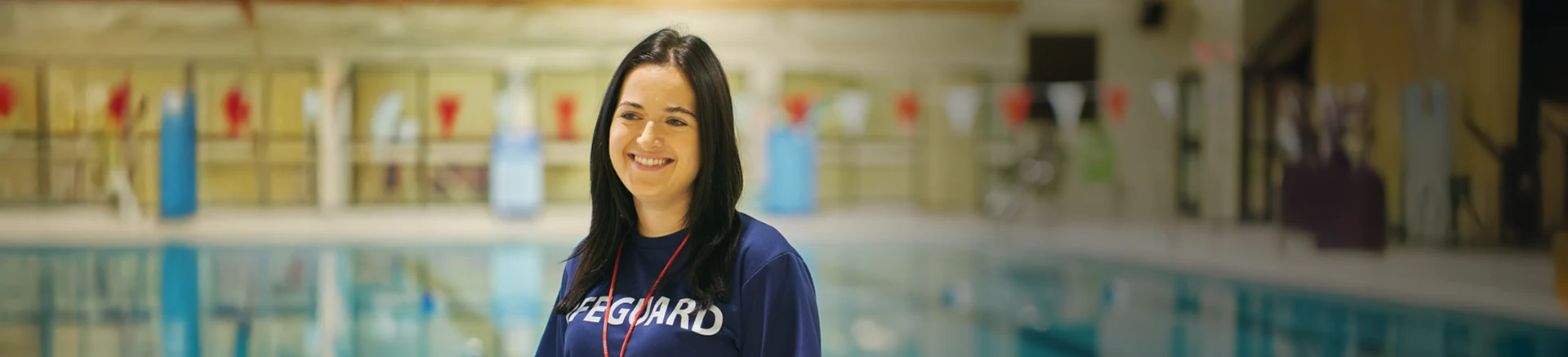 A lifeguard standing in front of an indoor pool