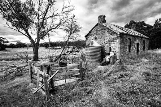 Photograph of old farm cottage with rusting water tank.