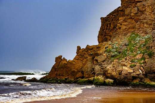 Photograph of headland with wave breaking just off shore.