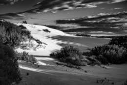 Photograph of dramatic sky above sand dune.