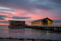 Photograph of the historic Queenscliff Pier at sunrise as viewed from the beach. The pier still features the under cover waiting area used for the famous bay ferries and paddle steamers that operated from the 1880s.