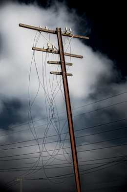 Photograph of leaning and aged power pole with disconnected lines.