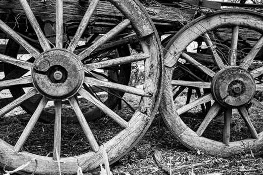 Black & White photograph of weathered wagon wheels.