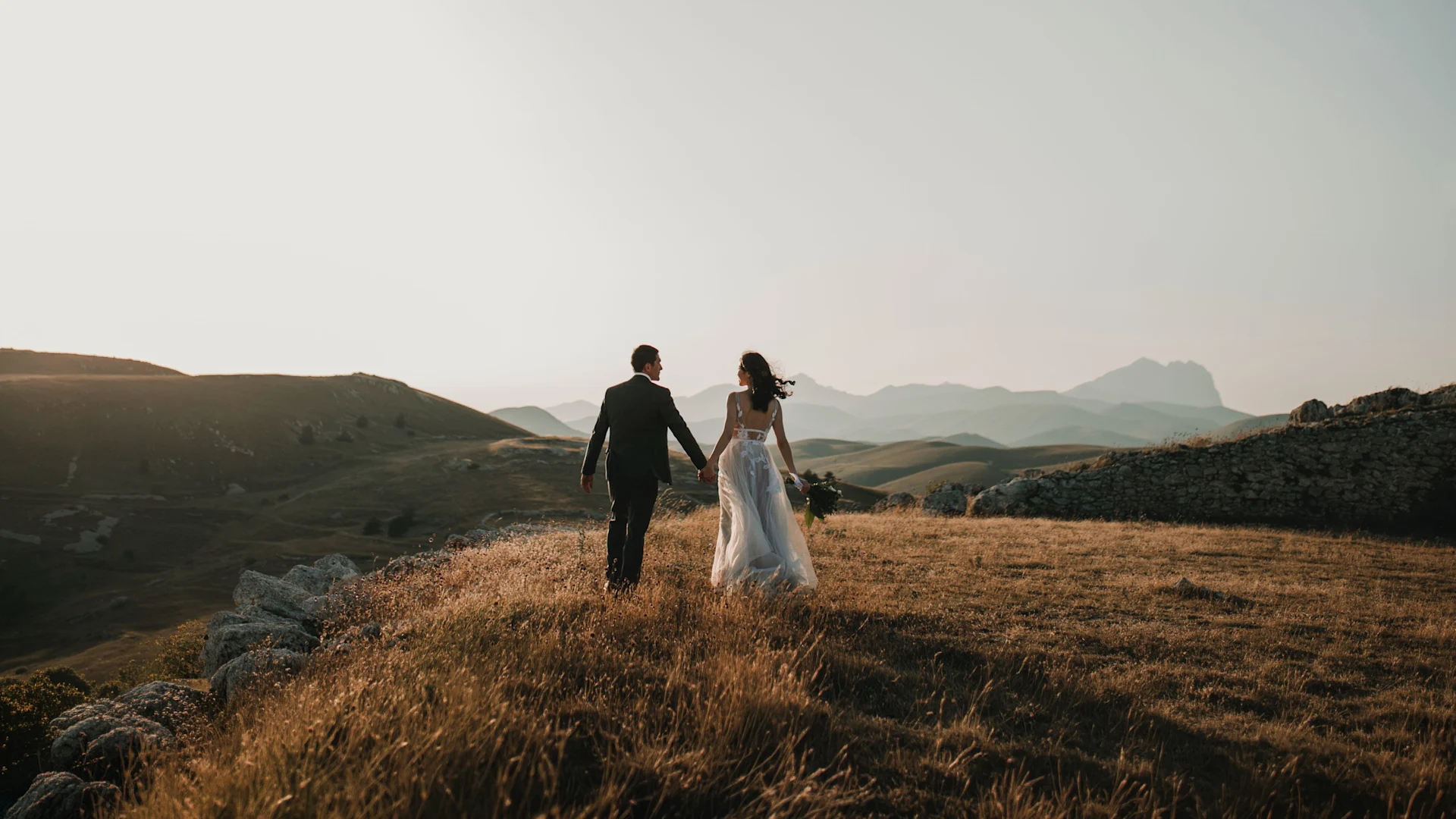 A couple embraces in wedding attire outdoors.