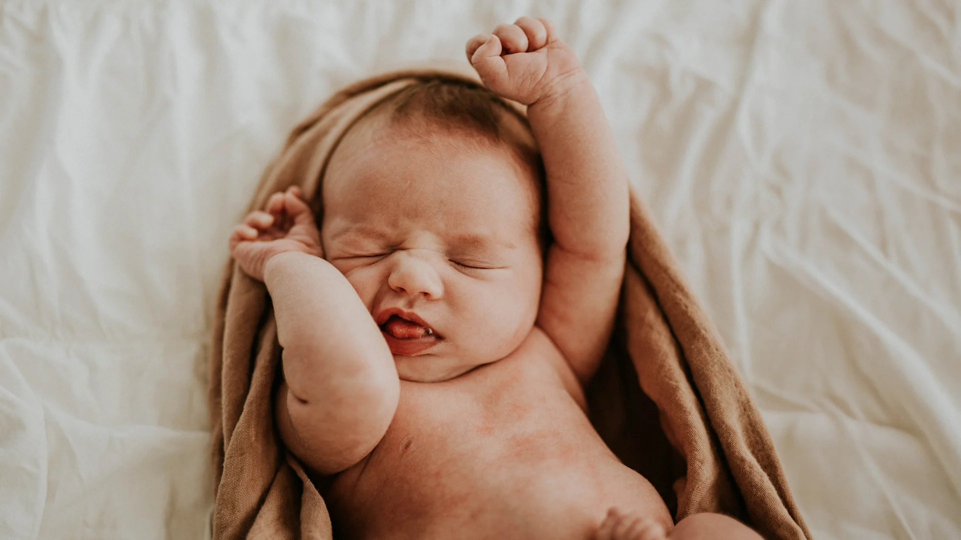 A sleeping baby wears a soft, knitted hood with bear ears.