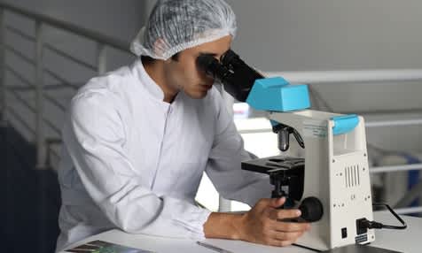 student scientist researcher in medical lab looking into microscope