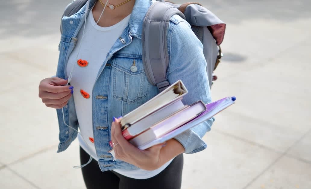 a young woman holding college books in hand