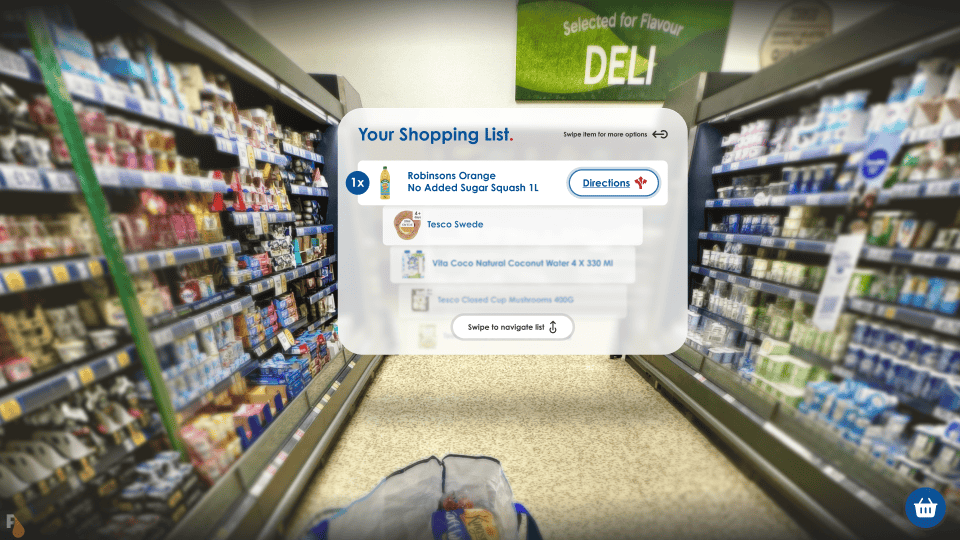 User perspective of a grocery aisle with an augmented reality overlay from Apple Vision Pro AR glasses displaying a shopping list with items such as Robinsons Orange No Added Sugar Squash, Tesco Swede, Vita Coco Natural Coconut Water, and Tesco Closed Cup Mushrooms, including a directions icon for navigation.