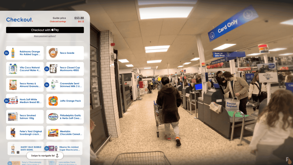 View inside a supermarket at the checkout area with an augmented reality display from Apple Vision Pro AR glasses showing a checkout interface with a total guide price, savings, and an option to pay using Apple Pay, along with a scrollable list of grocery items such as Robinsons Orange No Added Sugar Squash and Tesco Closed Cup Mushrooms.