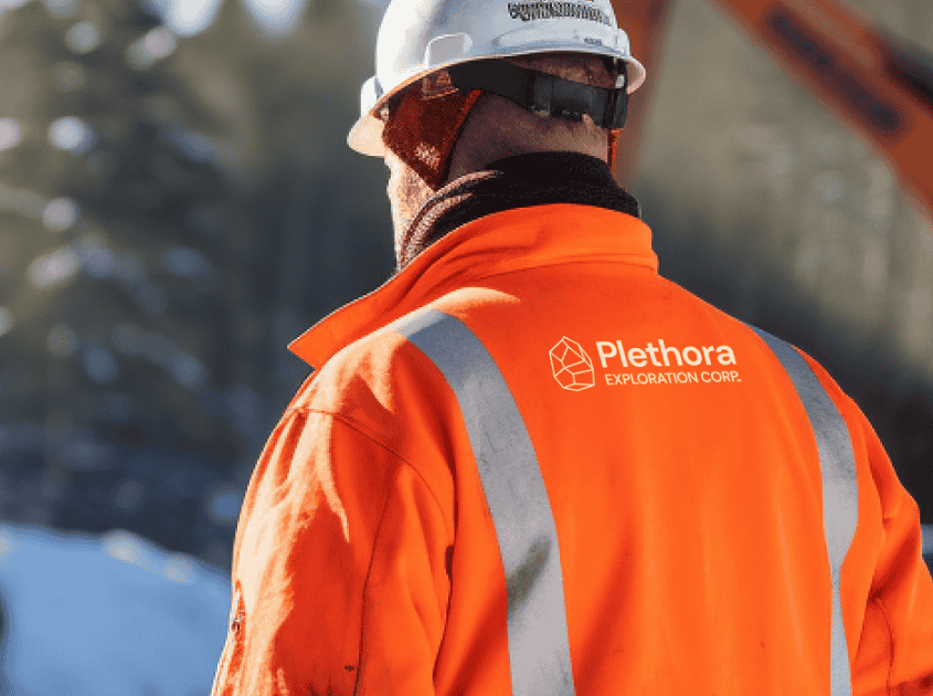 Worker wearing a high-visibility safety vest with the Plethora Exploration Corp logo on the back.