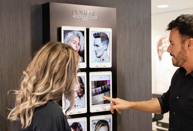 Hairdresser showing customer various hair colors on iPad