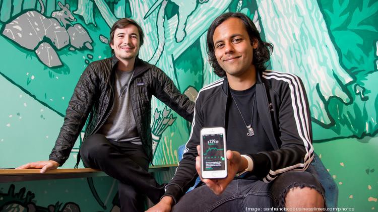 Robinhood founders standing in front of graffiti wall with a phone