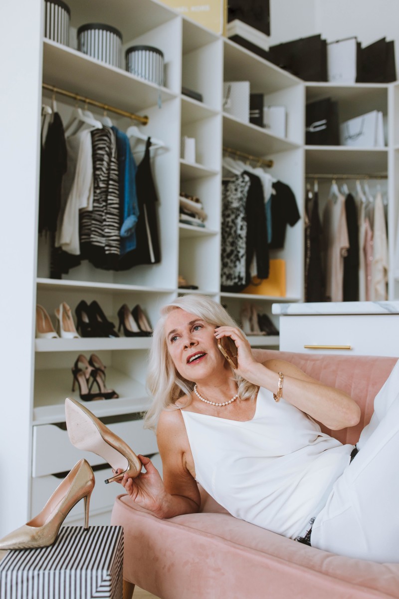 Woman with white hair reclining on a pink sofa in her closet