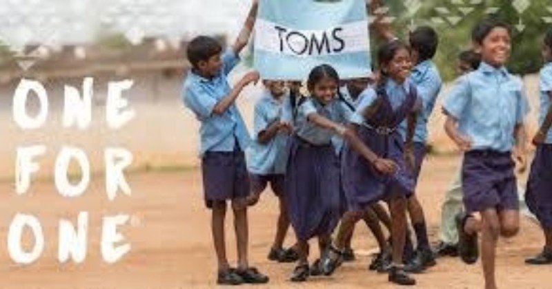 Children holding up flag of TOMS logo
