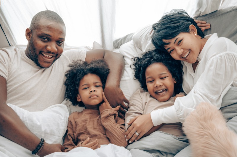 Image of a diverse family laying in a bed