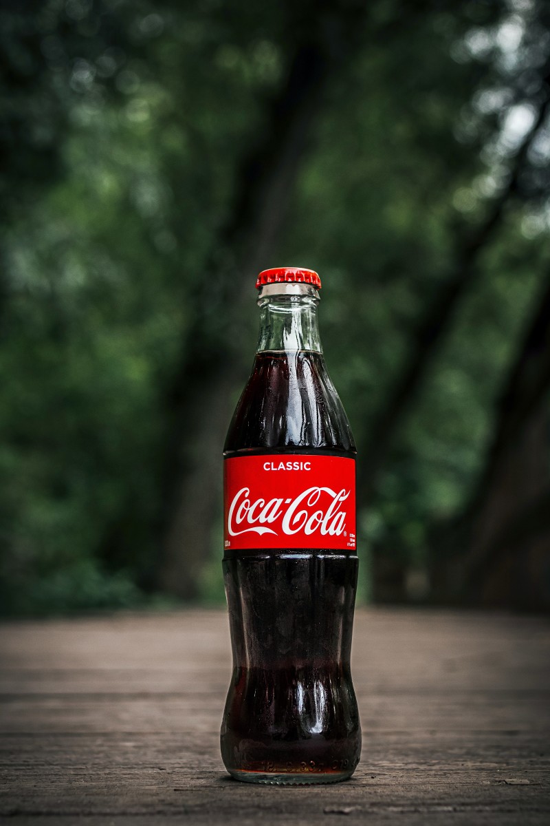Coca-Cola glass bottle placed on the ground in a forest