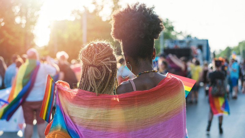 Two women embracing under a rainbow flag