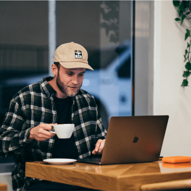 Man with Coffee and hat, working on laptop