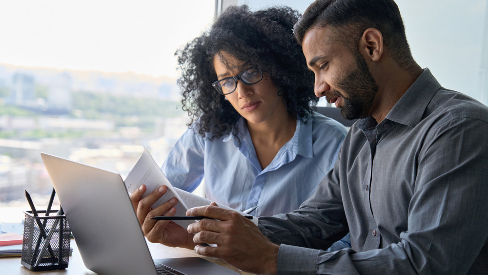 Two People looking at a laptop and papers